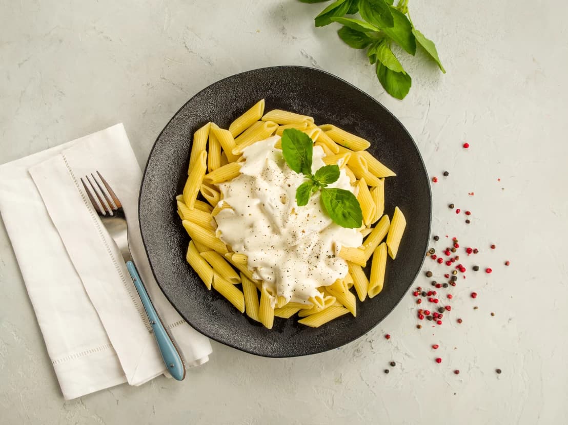 Massa com molho branco cremoso em prato fundo