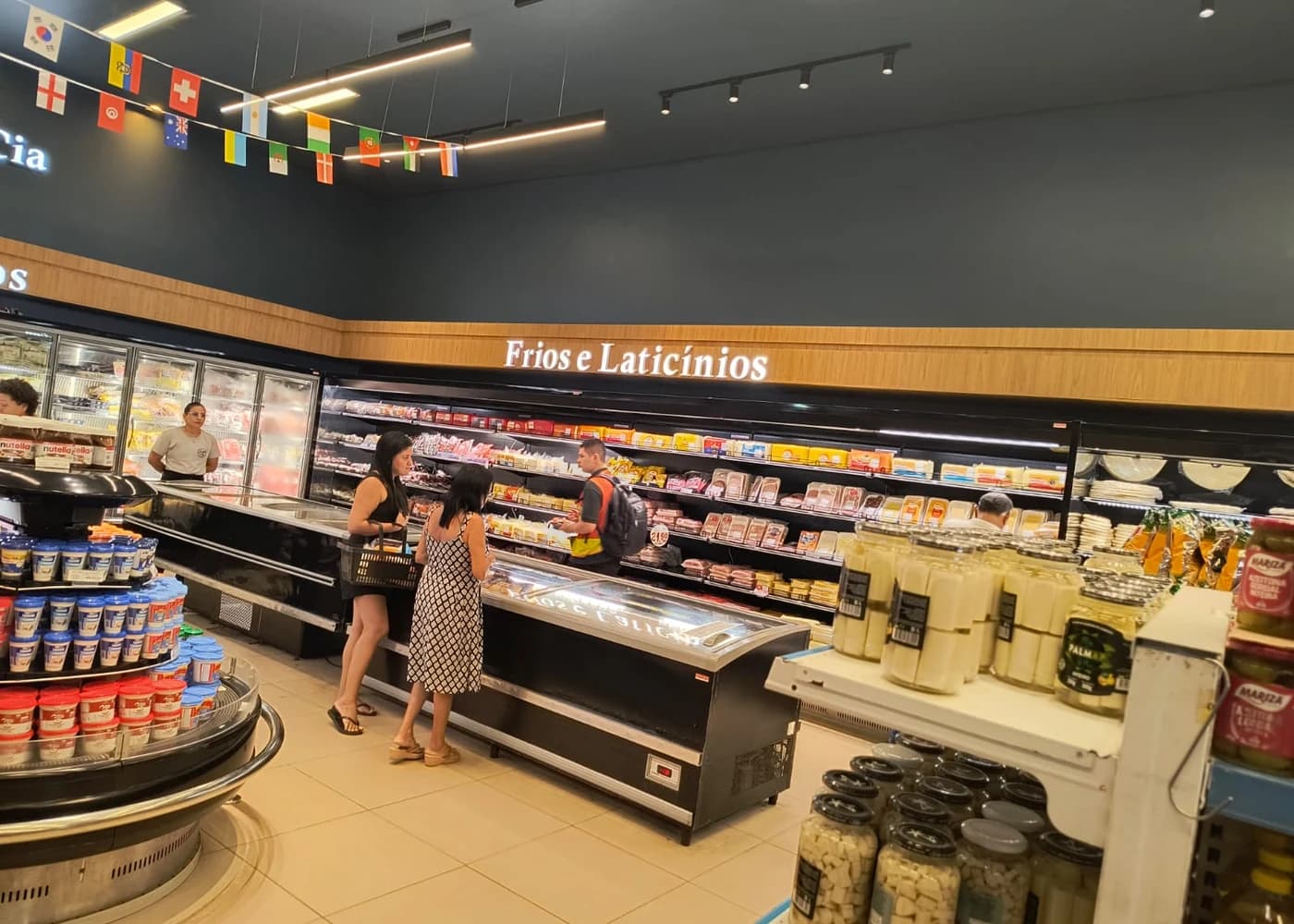 Balcão de Frios e Laticínios da Queijo & Cia, atendente ajudando uma cliente